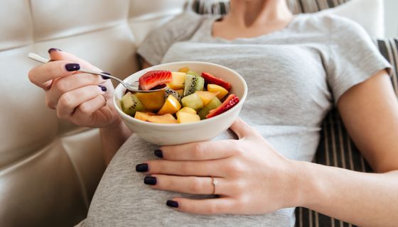 Junge schwangere Frau, isst einen Obstsalat.