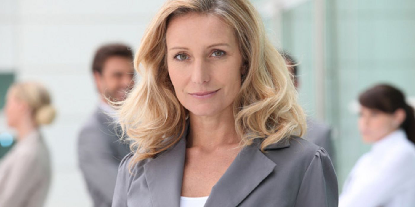 Blonde Businessfrau in grauem Kostüm