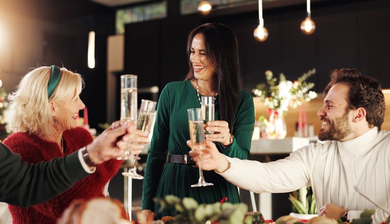 Eine Familie feiert Weihnachten mit erhobenen, gefüllten Sektgläsern.
