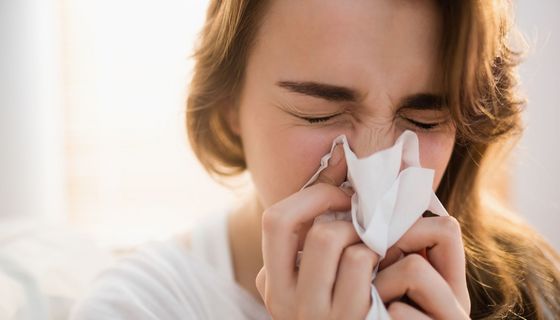 Frau putzt sich die Nase.