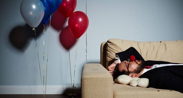 Mann, liegt nach einer durchzechten Nacht auf der Couch und schläft.