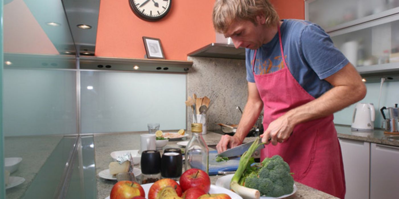 Mann in der Küche beim Schneiden von Gemüse