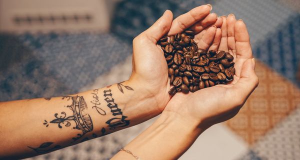 Frau, hält Kaffeebohnen in der Hand.