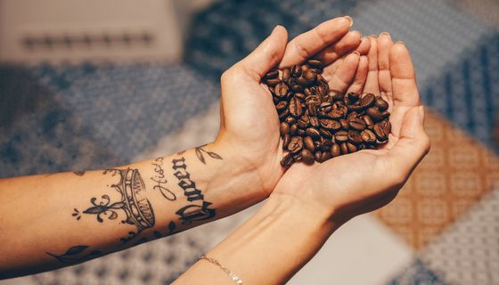 Frau, hält Kaffeebohnen in der Hand.