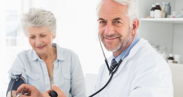 Arzt misst einer älteren Frau den Blutdruck