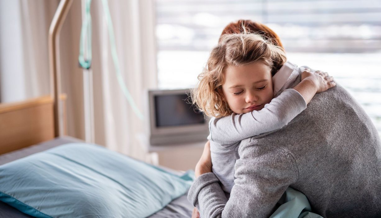 Mutter, umarmt ihre Tochter im Krankenhausbett.