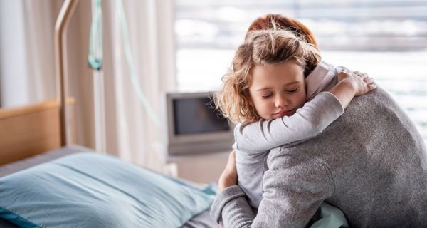 Mutter, umarmt ihre Tochter im Krankenhausbett.