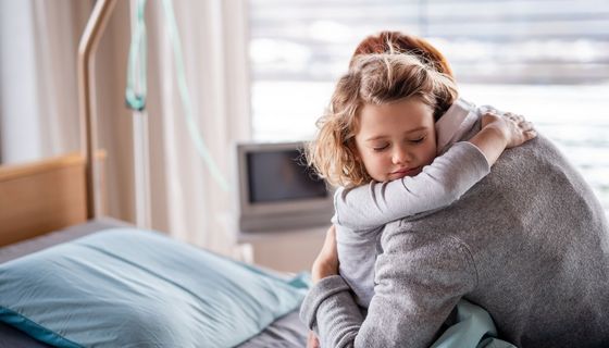 Mutter, umarmt ihre Tochter im Krankenhausbett.