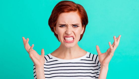 Frau mit wütendem Gesichtsausdruck wirft die Arme in die Luft.