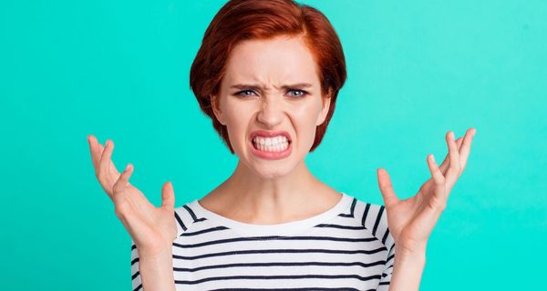 Frau mit wütendem Gesichtsausdruck wirft die Arme in die Luft.