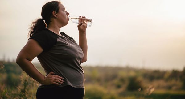 Übergewichtige Frau, trinkt Wasser.