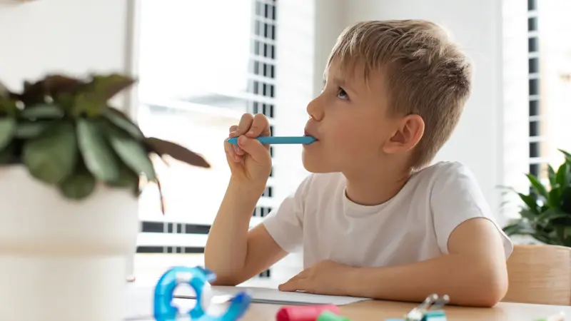 Junge, kaut an seinem Stift.