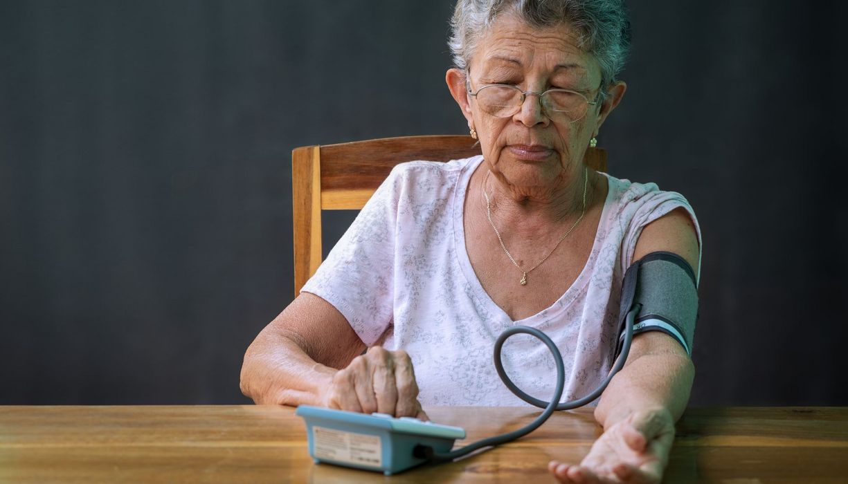 Ältere Frau, misst ihren Blutdruck.