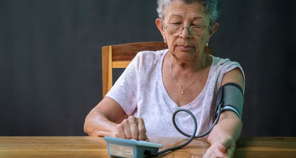 Ältere Frau, misst ihren Blutdruck.