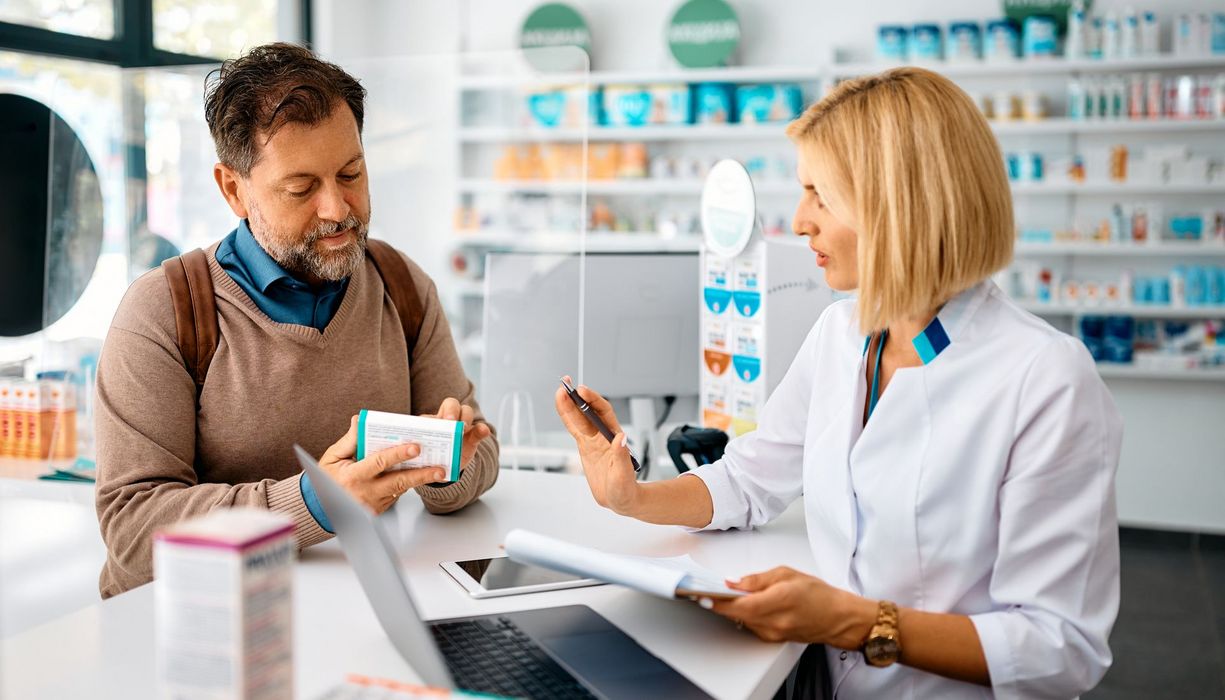 Apothekerin berät einen Kunden zu einem Medikament.