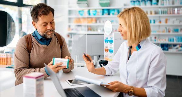Apothekerin berät einen Kunden zu einem Medikament.