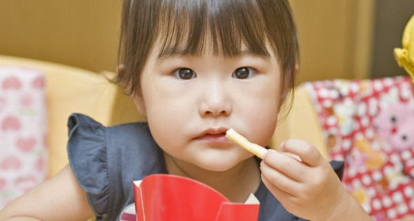 Asiatisches, kleines Mädchen isst Pommes