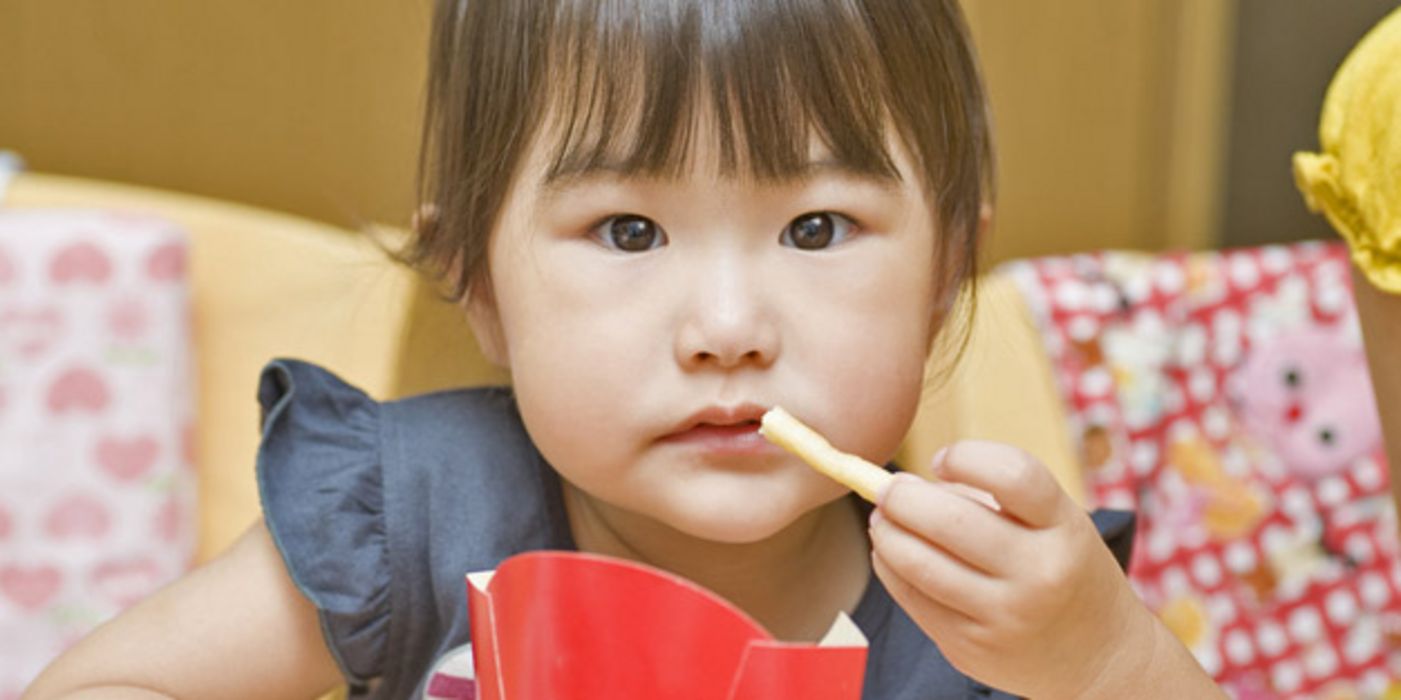 Asiatisches, kleines Mädchen isst Pommes