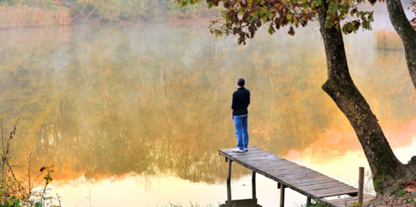 Herbststimmung, Waldsee, Mann steht auf Holzsteg mit Rücken zur Kamera