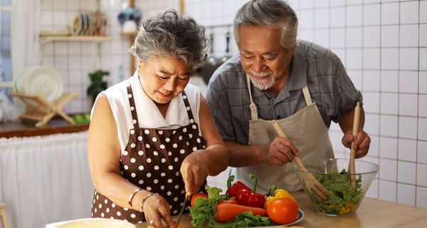 Ein älteres Paar, macht zusammen in der Küche Salat. 