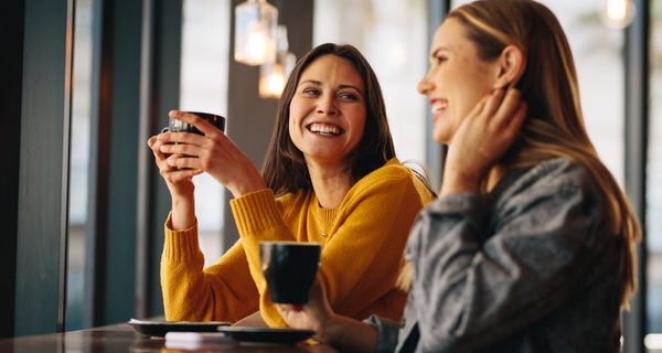 Zwei Freundinnen, trinken Kaffee und sprechen miteinander.