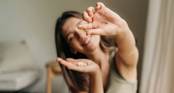 Frau, hält eine Vitaminpille in die Kamera.