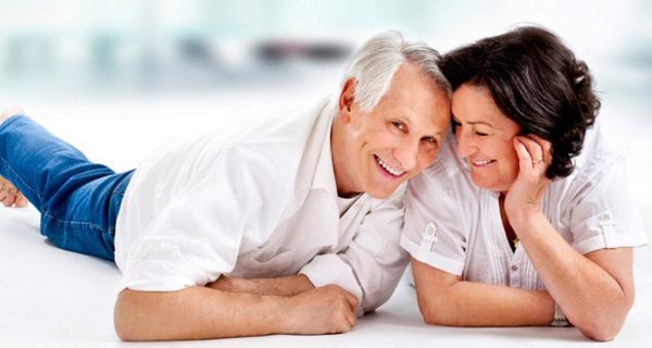 Älteres, zufriedenes Ehepaar liegt bäuchlings auf dem Boden