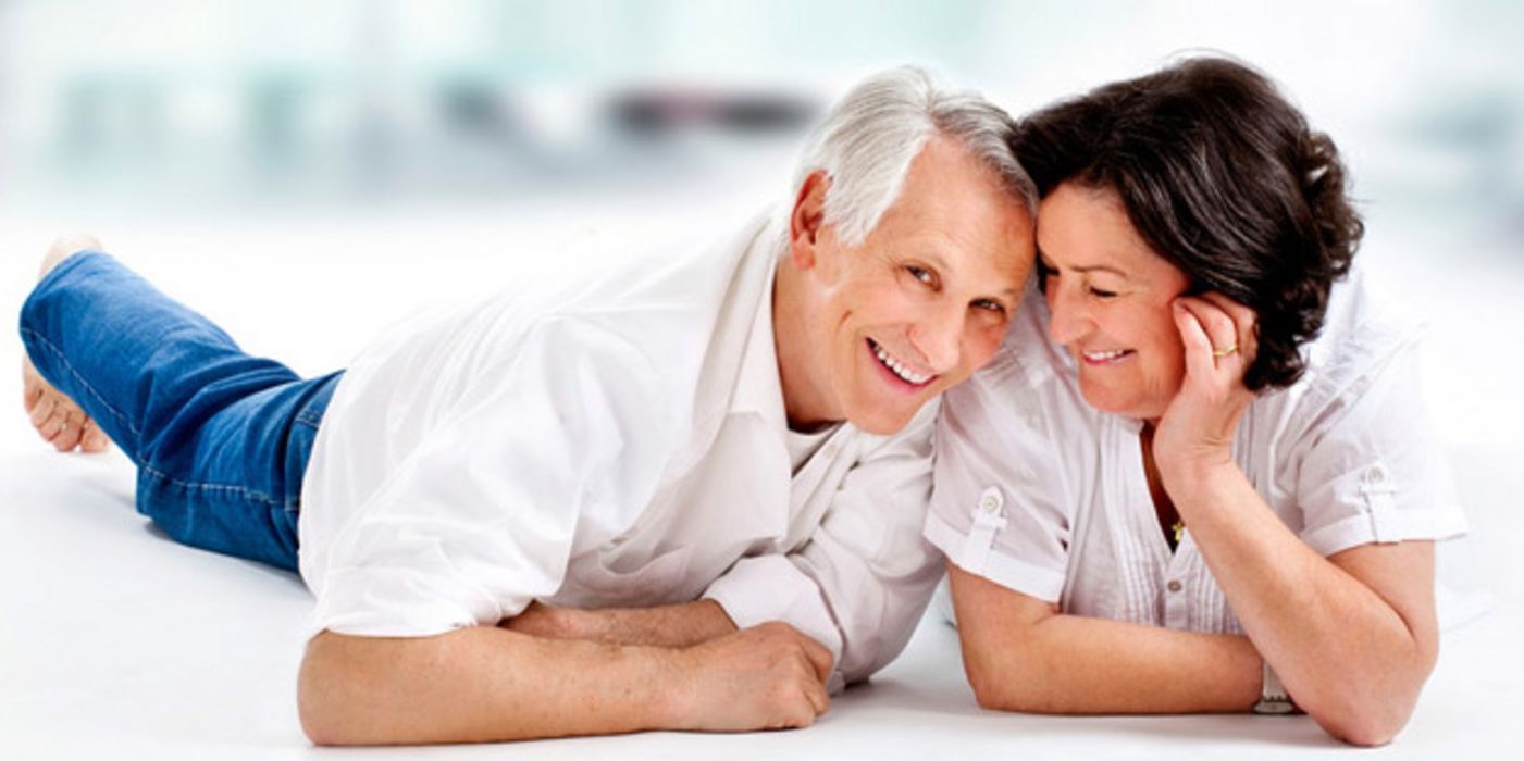Älteres, zufriedenes Ehepaar liegt bäuchlings auf dem Boden
