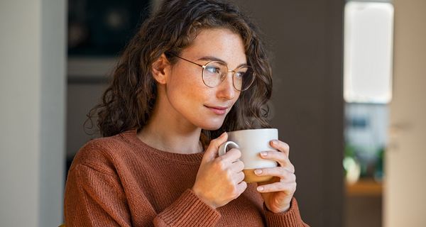 Junge Frau mit Brille trinkt Tee.