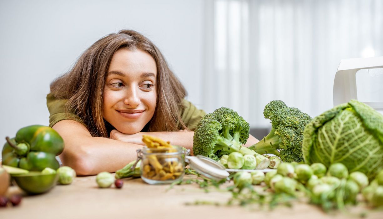 Frau schielt auf grünes Gemüse und lächelt.