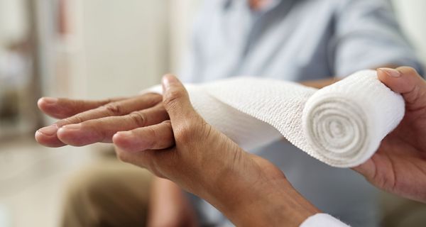 Arzt, verbindet die Hand eines Patienten.