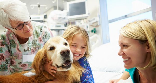 Kind in der Klinik, umarmt einen Hund.