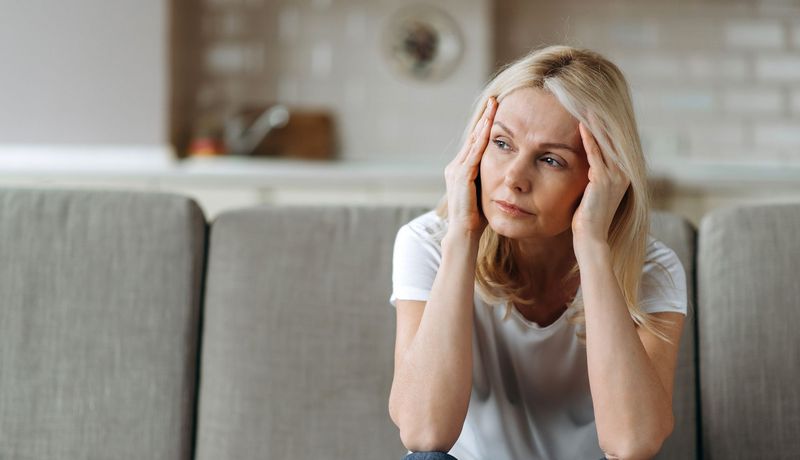 Erschöpfte Frau sitzt auf einem Sofa.