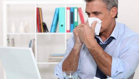 Erkälteter Mann mittleren Alters im Büro