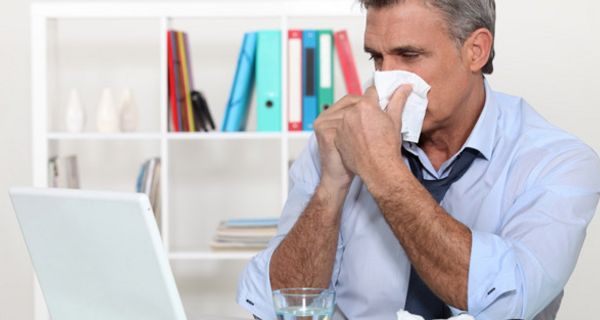 Erkälteter Mann mittleren Alters im Büro