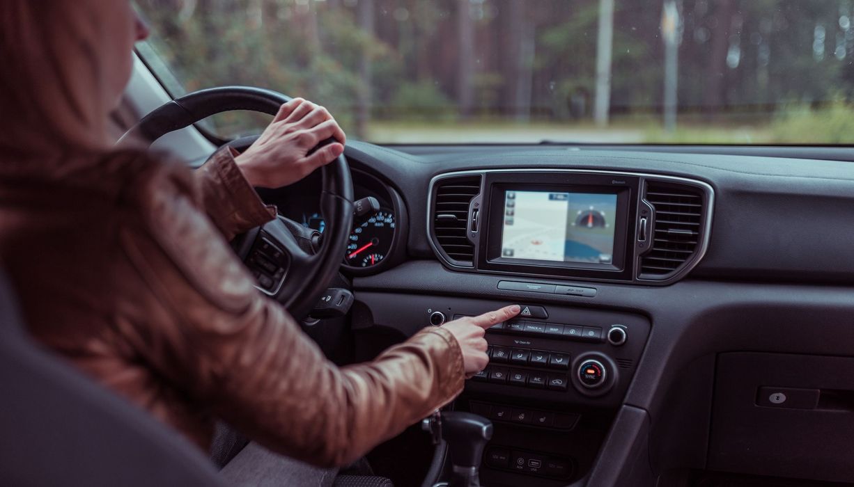 Frau, sitzt in einem Auto und bedient ihr Navi.