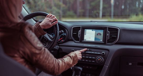 Frau, sitzt in einem Auto und bedient ihr Navi.