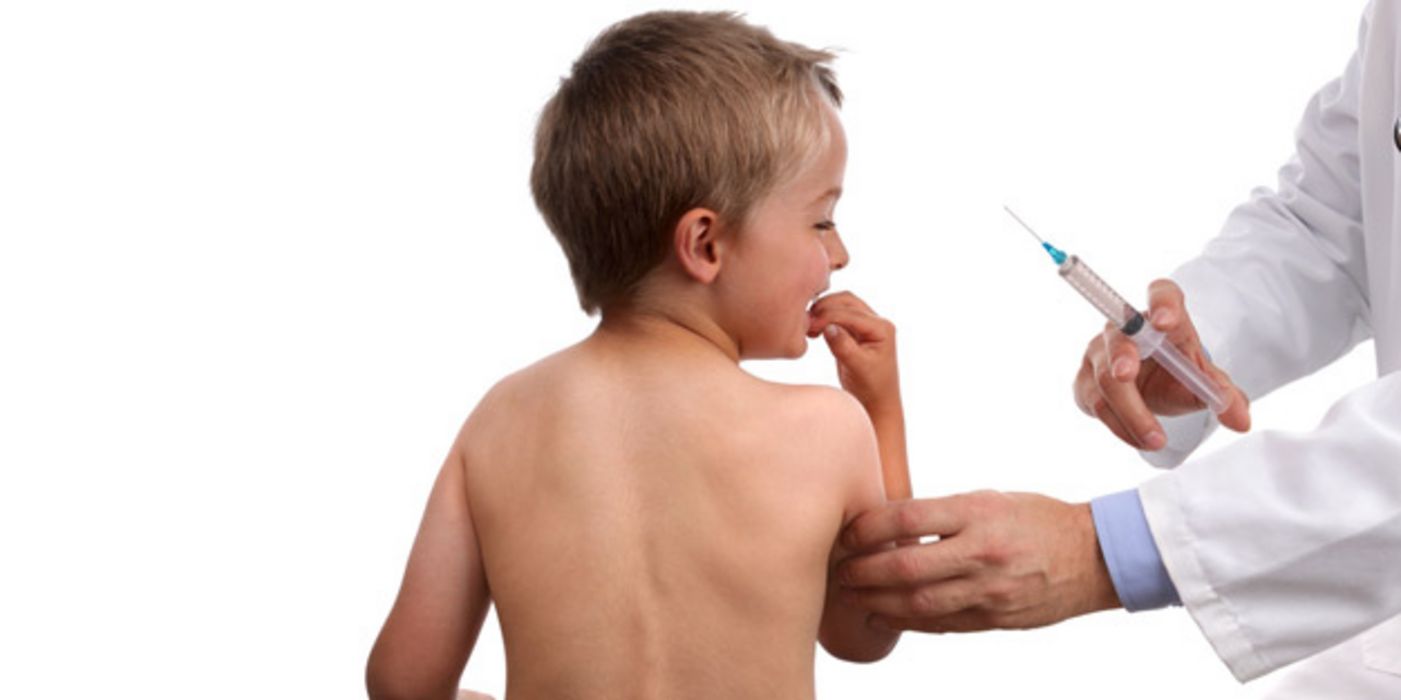 Nackter Rücken eines Jungen, ca. 7 Jahre alt, Arm im Arztkittel mit Spritze in der Hand. Junge macht ein ängstliches Gesicht und hat eine Hand am Mund