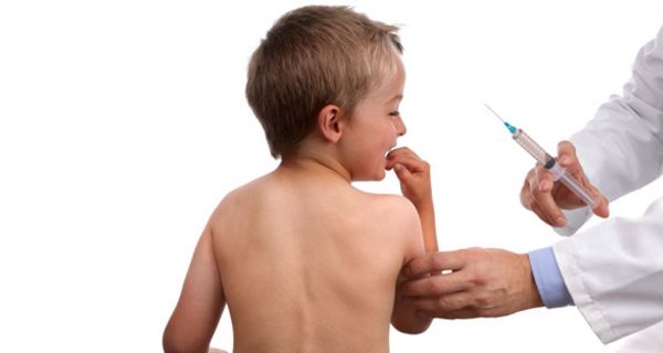 Nackter Rücken eines Jungen, ca. 7 Jahre alt, Arm im Arztkittel mit Spritze in der Hand. Junge macht ein ängstliches Gesicht und hat eine Hand am Mund