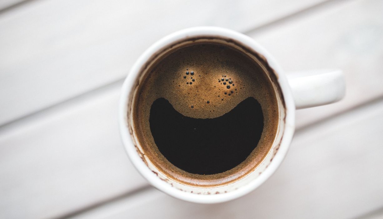 Schwarzer Kaffee mit einem lächelnden Gesicht als Schaum.