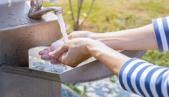 Eine Person wäscht sich die Hände an einem sauberen Außenwaschbecken im Freien. 