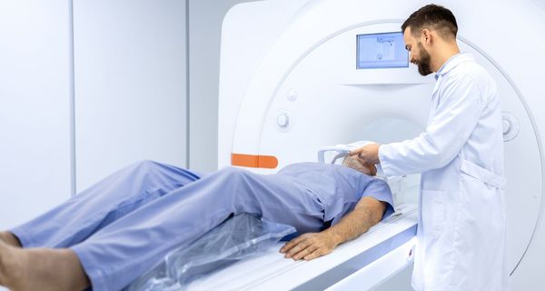 Medizinisches Fachpersonal bereitet einen Mann auf seinen MRT-Scan vor.