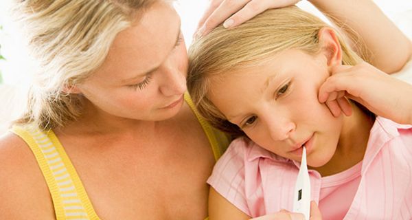 Mutter misst bei Schulkind (Mädchen, ca. 9 Jahre) Fieber und stützt mit einer Hand ihren Kopf. Beide sind blond.