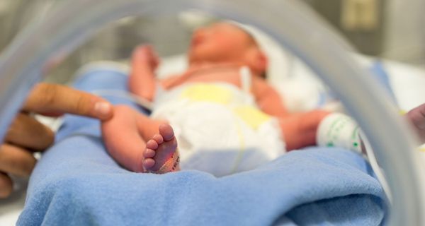 Foto von Neugeborenem im Klinikbettchen.