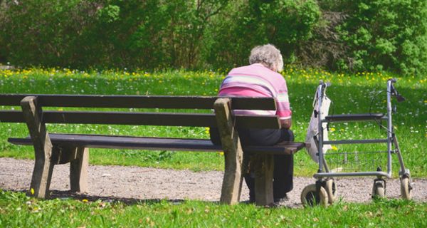 Alte Frau sitzt allein auf einer Parkbank
