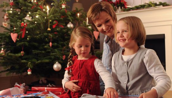 Mutter mit ihren zwei Töchtern bei der Bescherung unterm Weihnachtsbaum