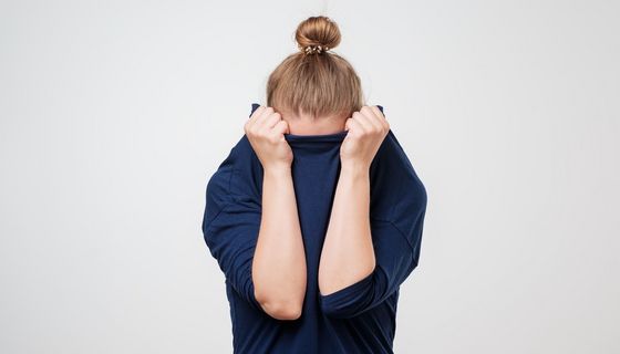 Junge Frau, verbirgt ihr Gesicht in ihrem Pullover.