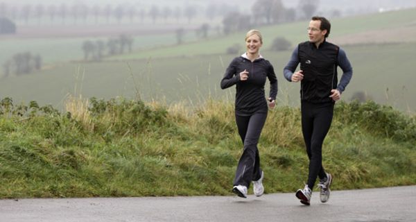 Mann und Frau joggen bei trübem Wetter über ein Feld