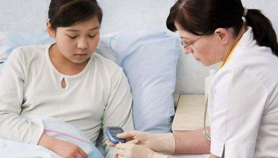 Krankenhausszene: Junge Patientin (asiatisch aussehend) bekommt von älterer Schwester oder Ärztin Blutzucker gemessen