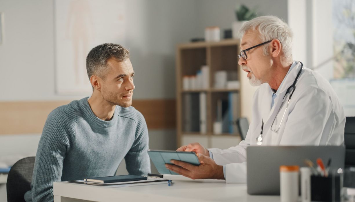 Ein Arzt erklärt einem Patienten etwas mithilfe seines Tablets.